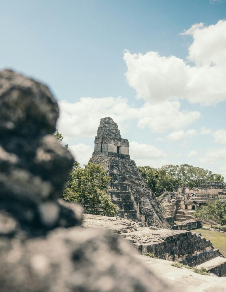 The Great Plaza of Tikal, flanked by Temple of the Great Jaguar (Temple I) and Temple of the Masks (Temple II), under a blue sky.