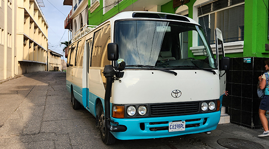 Spacious Ruwa Travels shuttle bus transporting travelers to Belize resorts and tours.